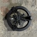 A used cast iron burner assembly or stove component with a circular ring, central support plate, and metal clips, resting on a concrete floor.
