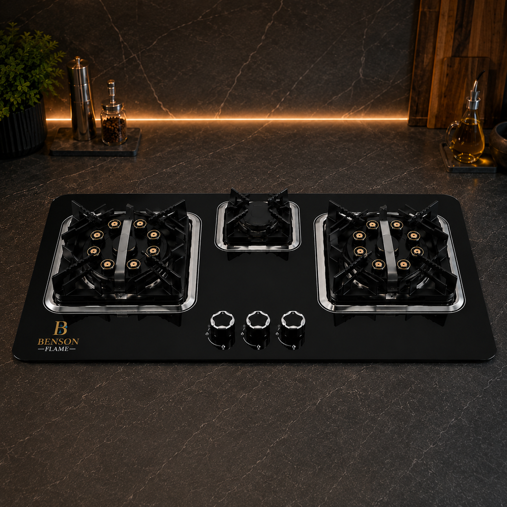 A black gas stovetop cooktop with three burners, silver metal trim, and three control knobs, shown lit with blue flames on a dark stone countertop. The brand name Benson Flame is visible in gold on the bottom left corner.